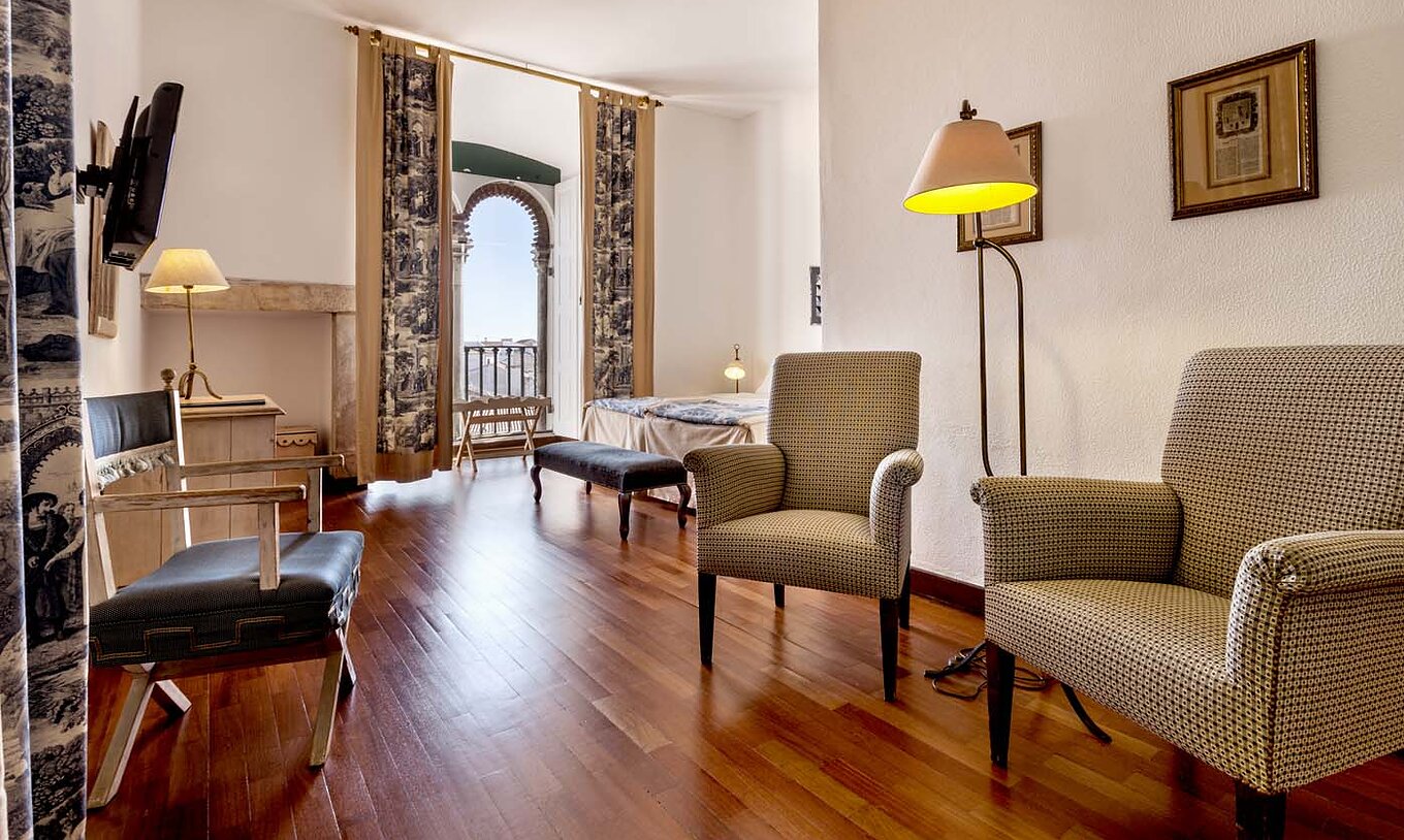 Le Chambre Supérieure de la Pousada Castelo Alvito a un couloir à l'entrée avec trois chaises, une télévision et tableaux