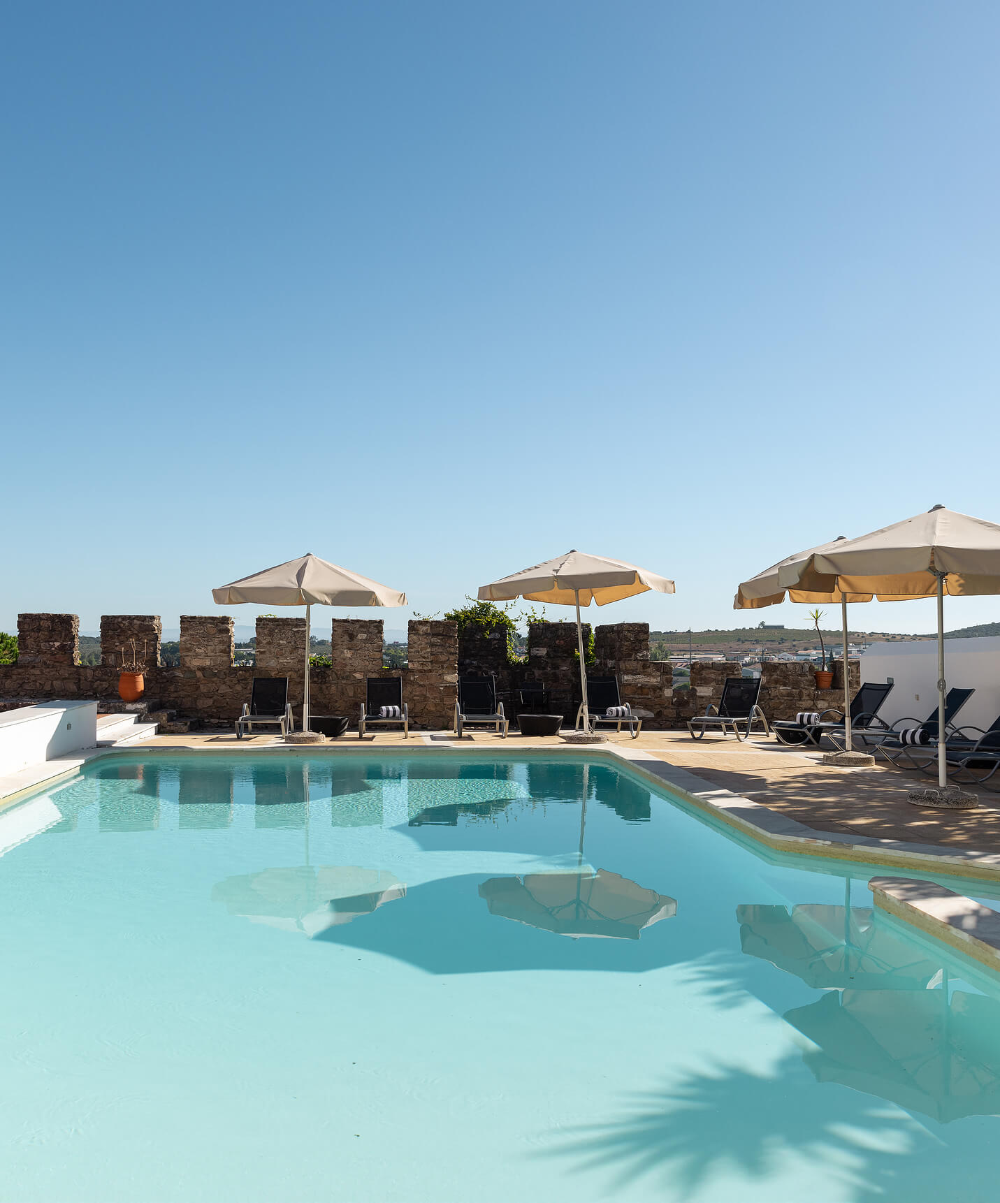 Vue de la piscine extérieure de l'hôtel dans le centre historique d'Estremoz avec chaises longues entourées de murailles