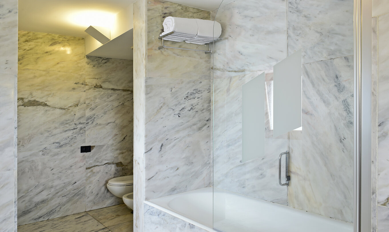 La Junior Suite de la Pousada Convento Arraiolos a une salle de bain en marbre clair, avec baignoire, toilettes et bidet