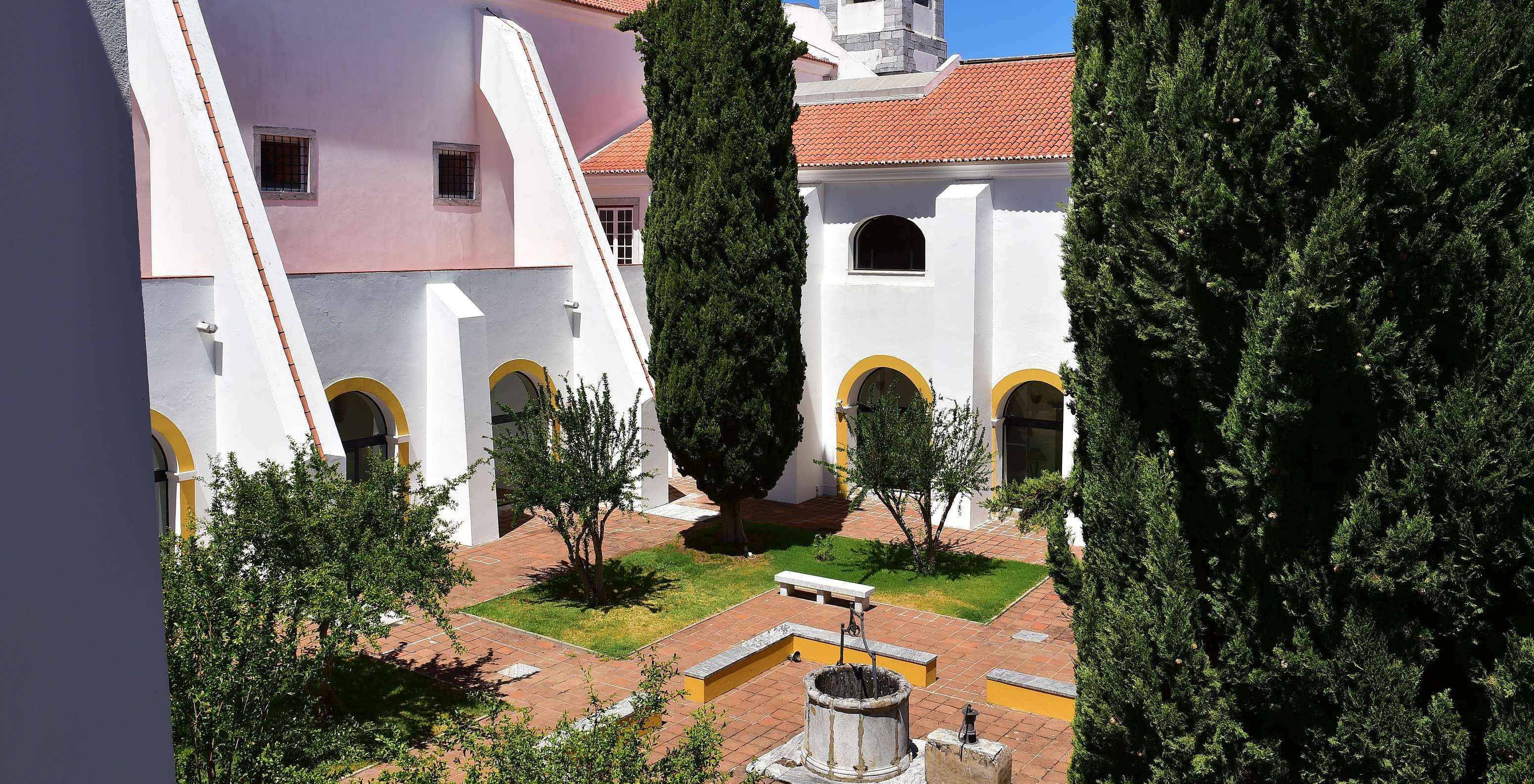 Jardin intérieur entre les cloître de la Pousada Convento Beja, avec différents arbres et un puits