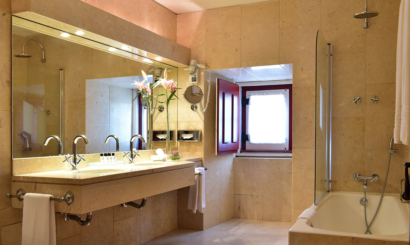La Suite Standard de la Pousada Convento Beja a une salle de bain spacieuse avec baignoire un grand miroir et deux lavabos
