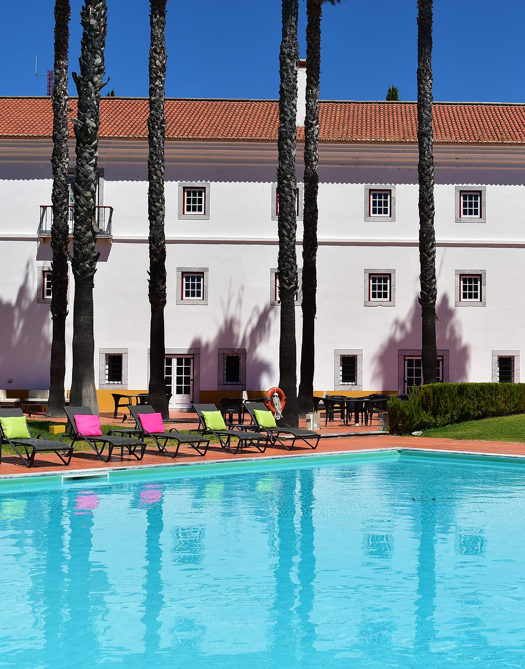 Piscine extérieure de la Pousada Convento Beja, un hôtel historique dans l'Alentejo, avec plusieurs transats avec coussins