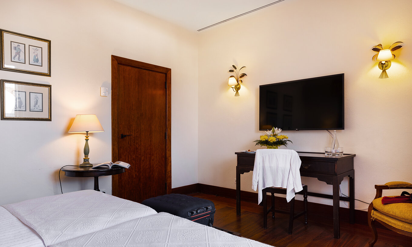 Le Chambre Classique de la Pousada Convento Vila Viçosa a une porte deux tableaux et une télévision en face des lits