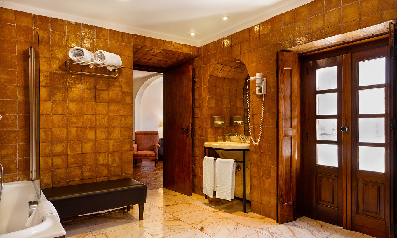 Le Supérieur Familial de la Pousada Convento Vila Viçosa a une salle de bain en tons terre avec un lavabo et un banc