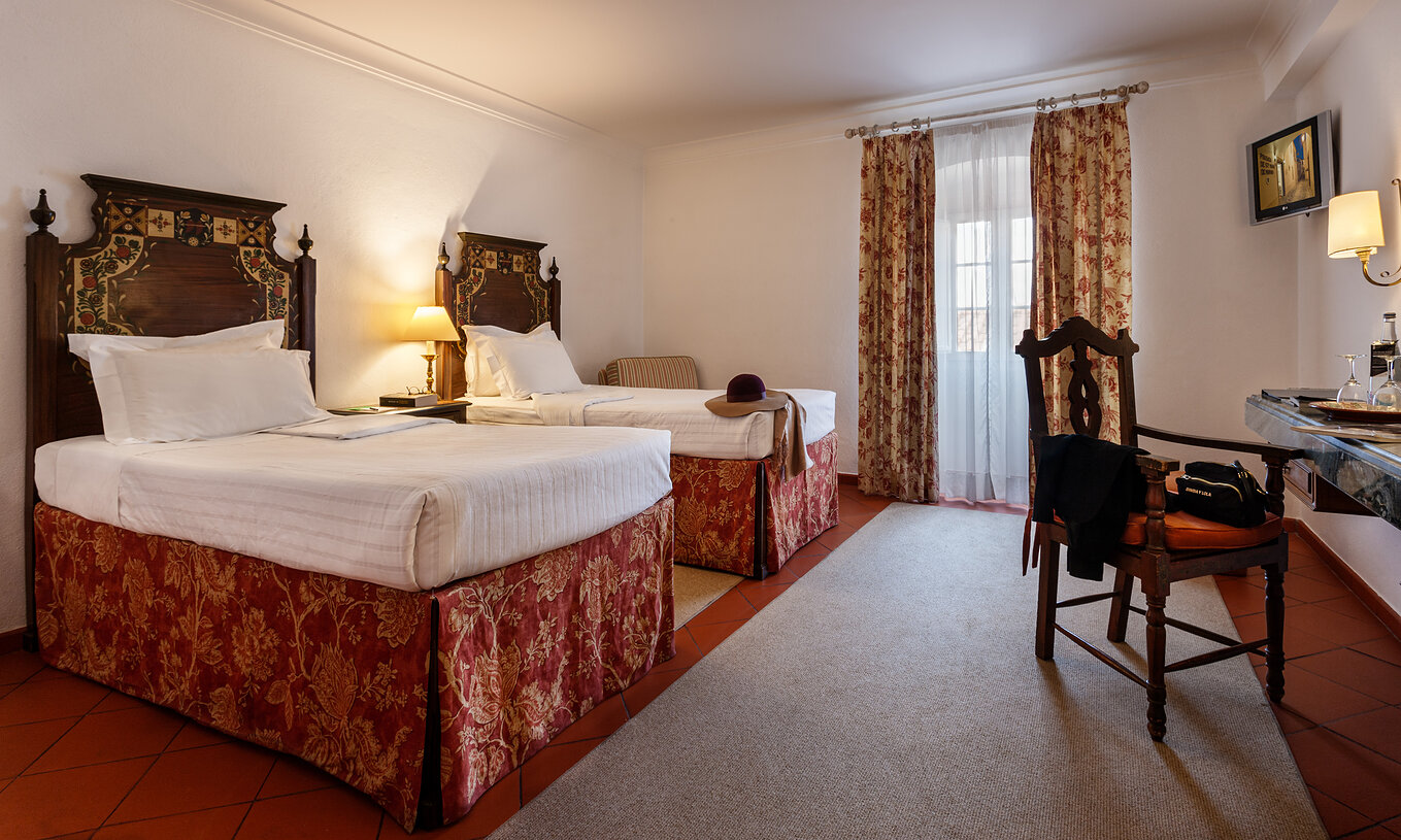 Le Chambre Familiale avec Balcon de la Pousada Marvão dispose de deux lits séparés à motif floral et d'un balcon