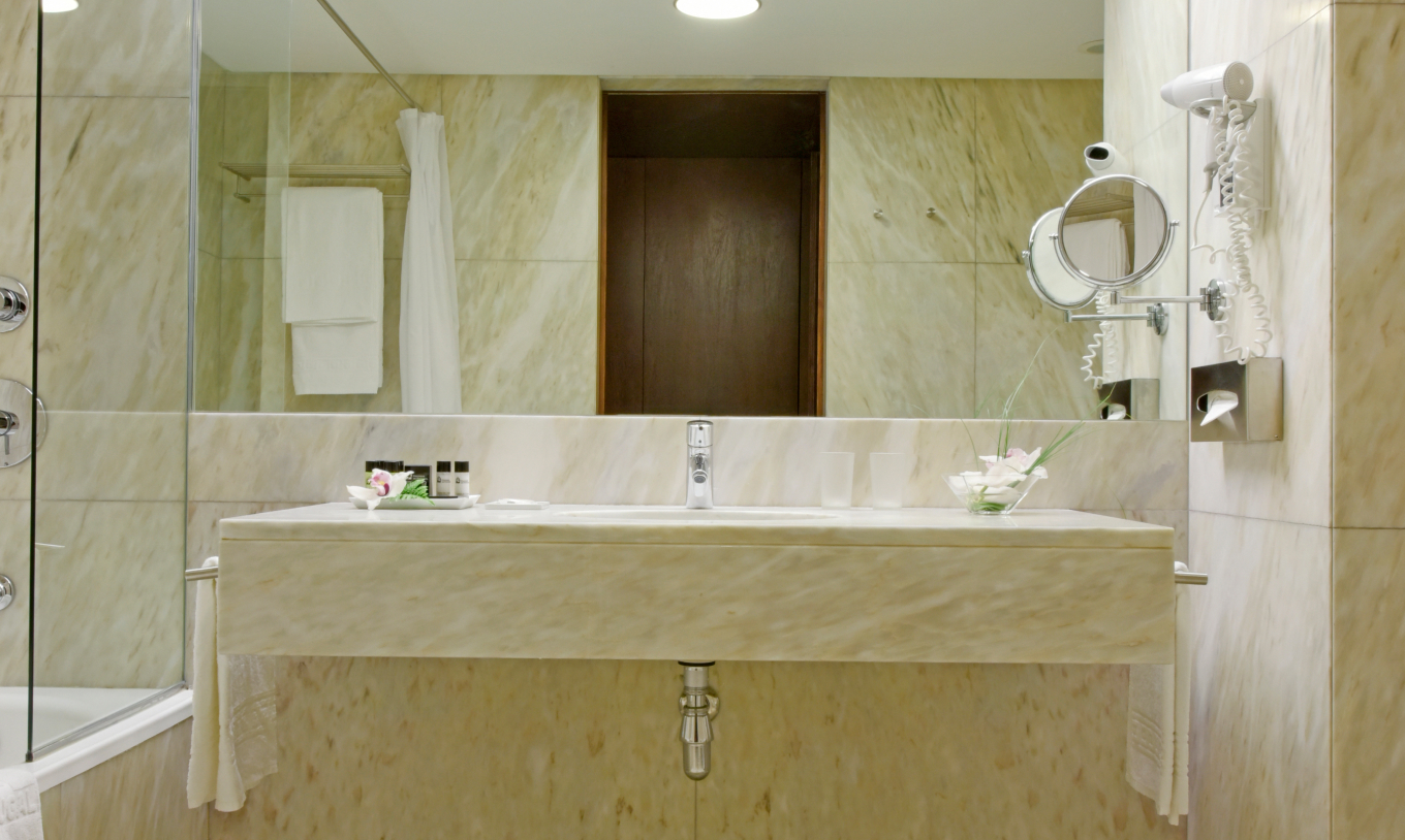 Le Chambre Classique de la Pousada Palácio Estoi a une salle de bain en marbre avec lavabo avec miroir et sèche-cheveux