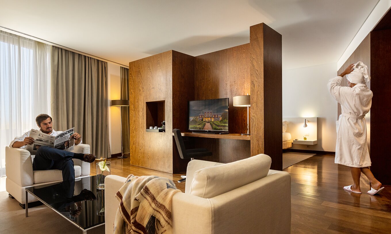 La Suite Vue Premium de la Pousada Palácio Estoi avec un homme lisant et une femme sortant d'un bain relaxant