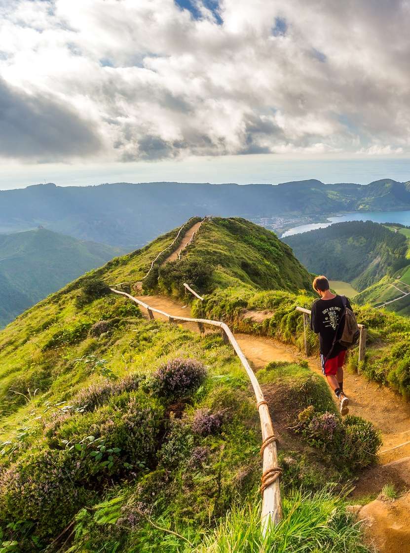 Homme marche sur un sentier de terre avec vue sur la lagune des Sept-Cités, île de São Miguel, Açores