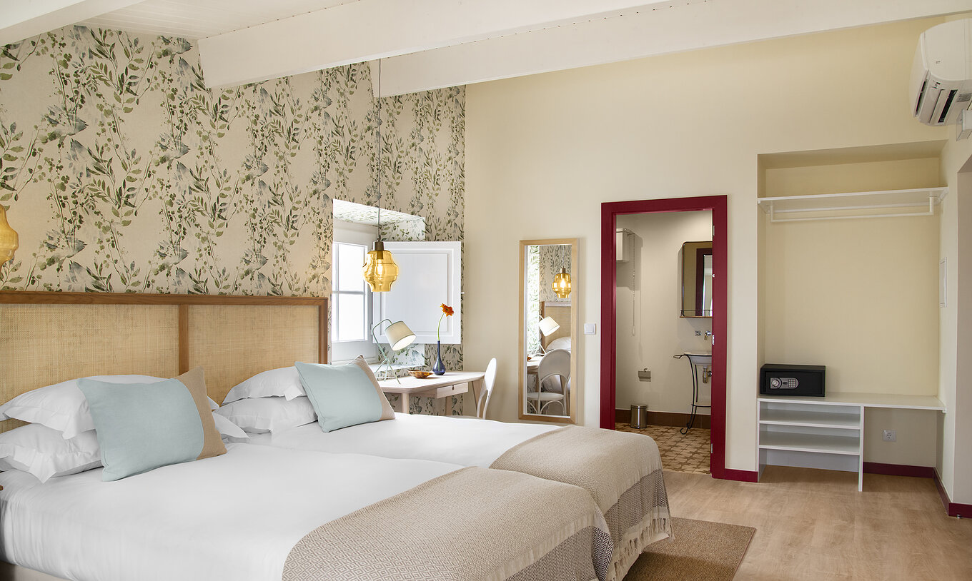 Le Chambre Familiale de la Casa Lidador - Óbidos a deux lits simples papier peint fleuri fenêtre et miroir au mur