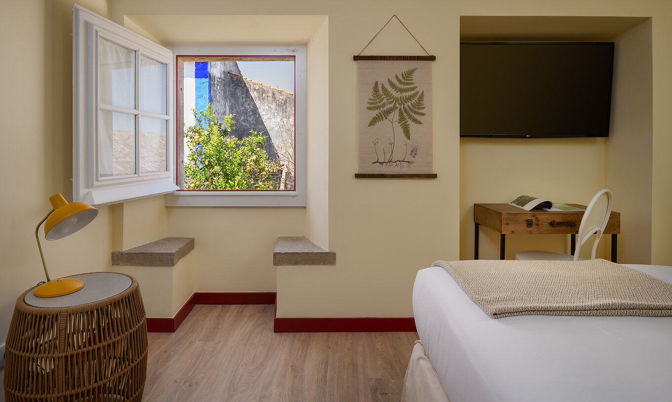 La Suite de la Casa Lidador - Óbidos a une télévision un bureau et une fenêtre carrée avec deux bancs en pierre