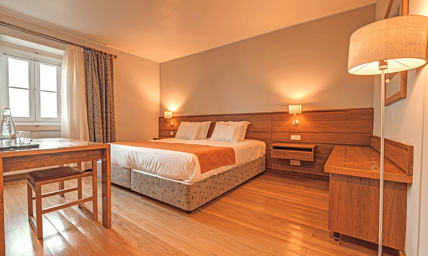 Le Chambre Supérieure de la Pousada Ourém a un lit double avec deux tables de nuit et un meuble de soutien à côté