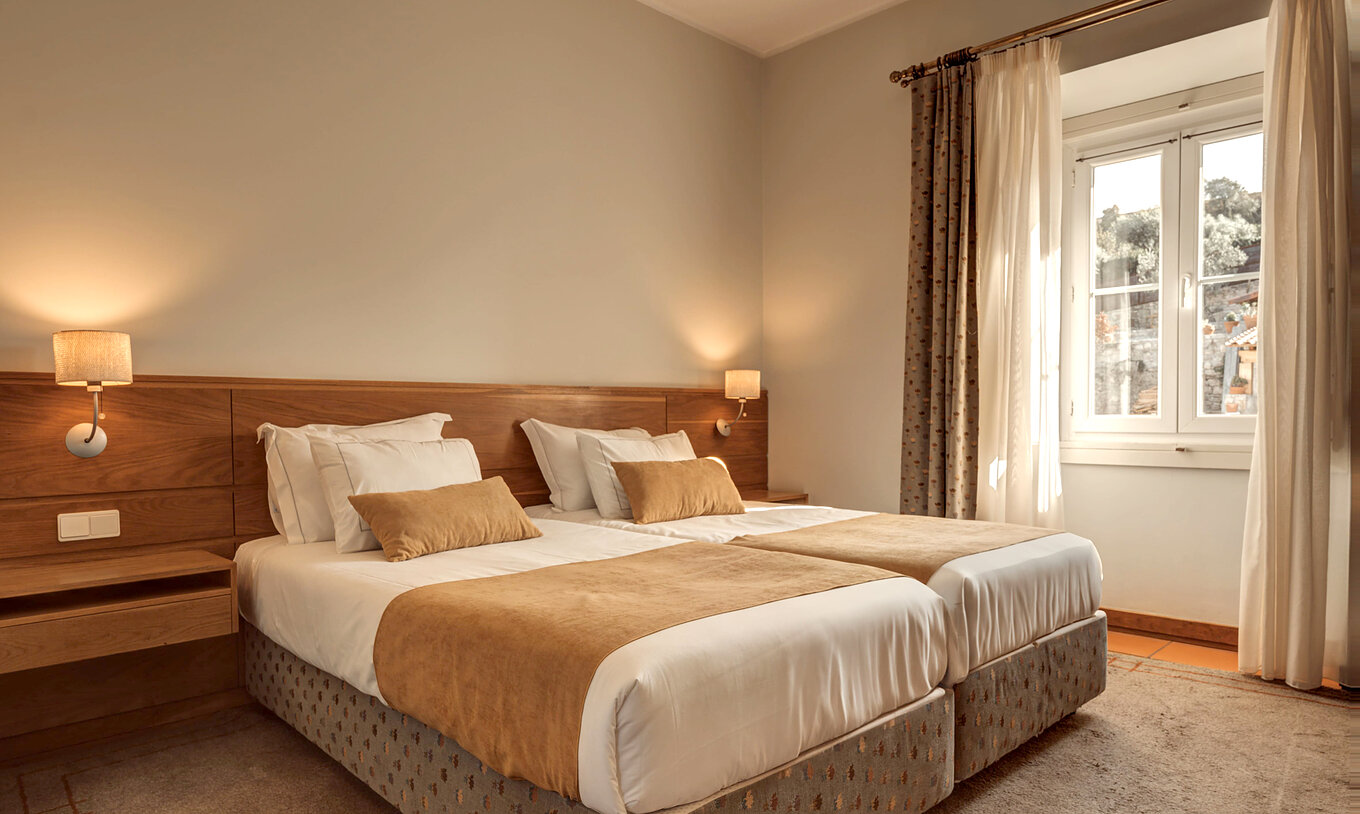 Le Chambre Supérieure de la Pousada Ourém a deux lits jumeaux avec une fenêtre à côté avec vue sur d'autres maisons