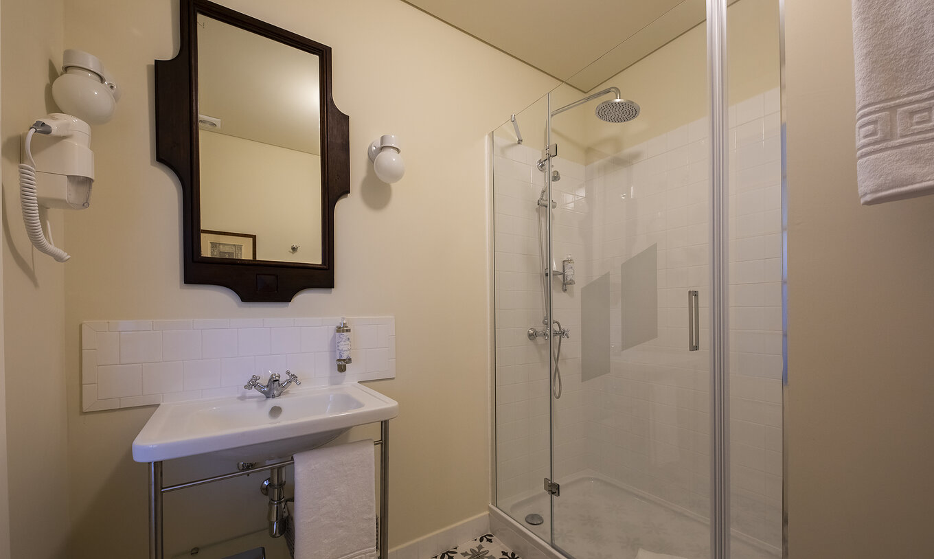Le Chambre Supérieure de la Pousada Vila Óbidos a une salle de bain avec douche, lavabo, miroir et sèche-cheveux