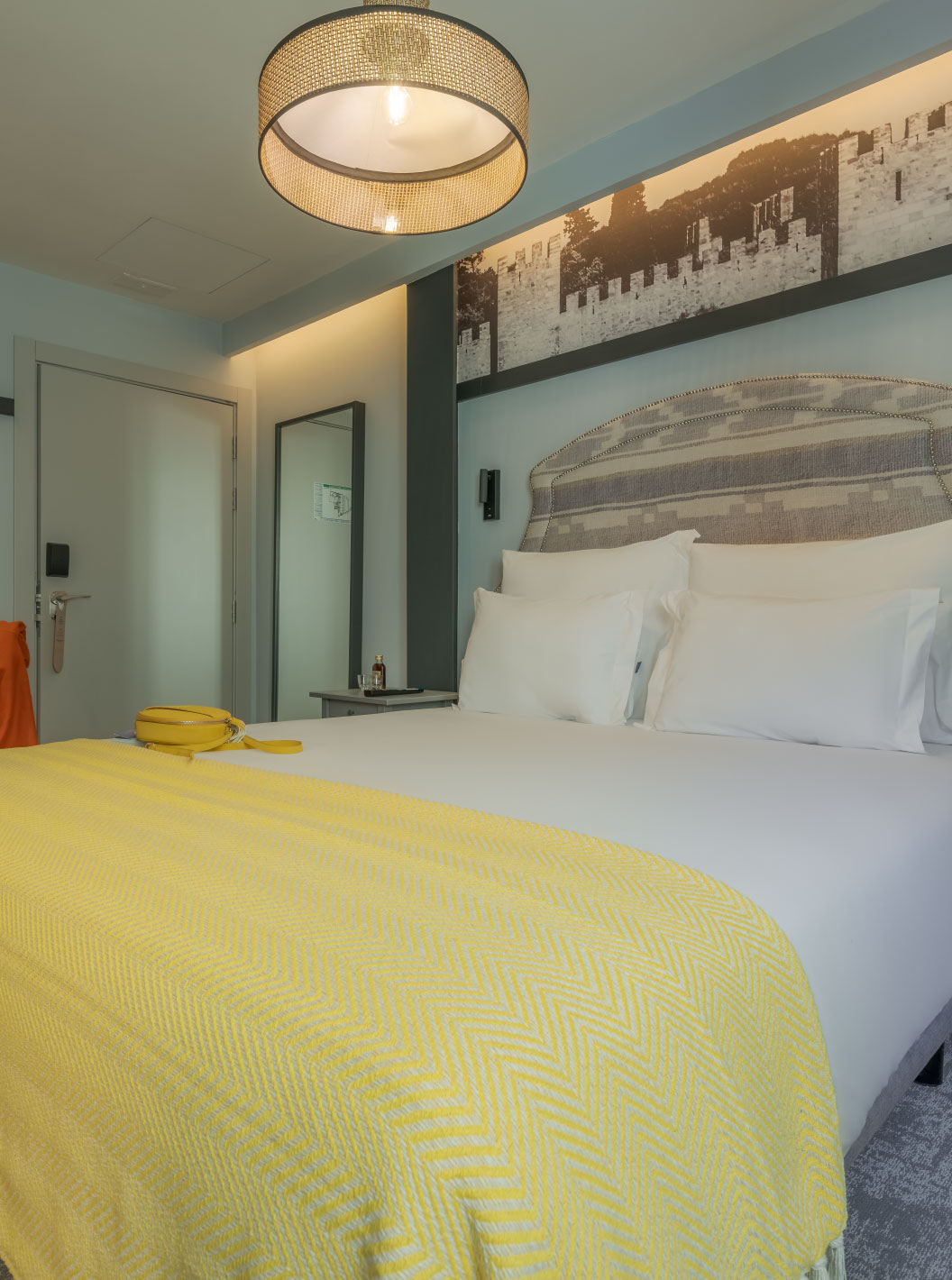 Cozy à Pousada Alfama a un lit double avec draps blancs, une couverture jaune et un fauteuil jaune