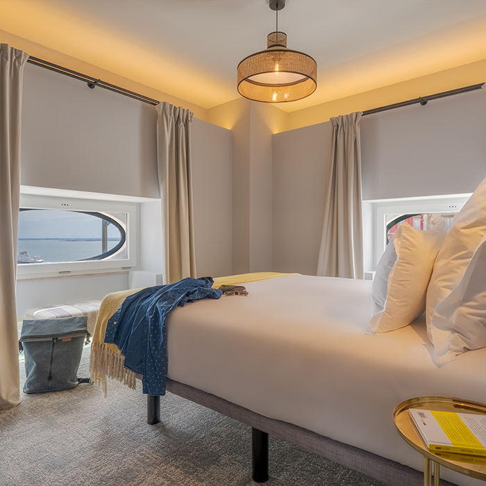 La Suite Portas do Sol de la Pousada Alfama a un lit double dans une chambre décorée en tons de jaune, avec une fenêtre ronde