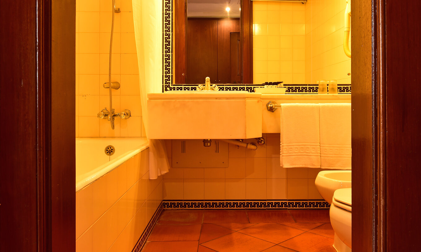 Le Clássico Famille de la Pousada Castelo Palmela a une salle de bain avec lavabo, miroir, baignoire et carrelage au mur