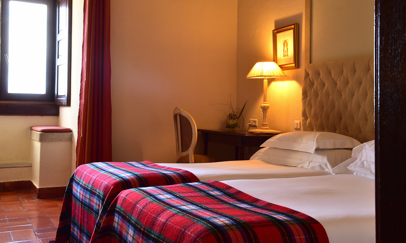 Le Chambre Supérieure de la Pousada Castelo Palmela a deux lits, un bureau en bois avec une lampe allumée et une fenêtre