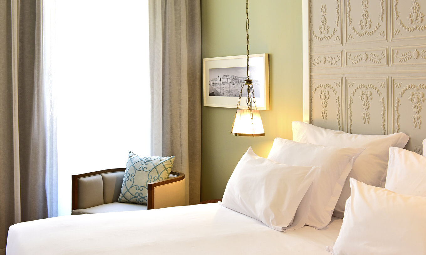 Le lit Deluxe King Size de la Pousada de Lisboa Praça do Comércio a lit double avec linge de lit blanc, fenêtre et fauteuil