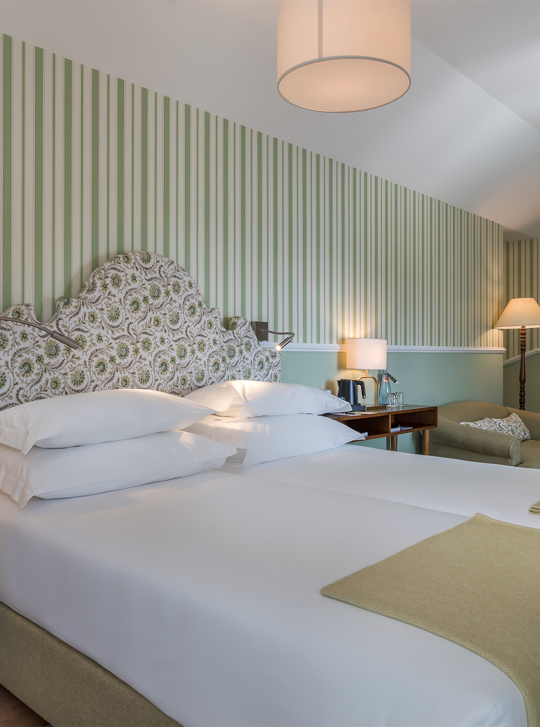 La Chambre Classique du Pestana Churchill Bay a un lit double, du papier peint rayé vert et un fauteuil confortable