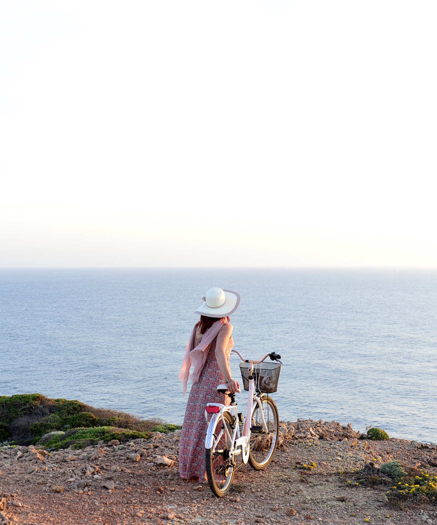 Femme se promenant avec un vélo à la main, le long des falaises de la côte portugaise, fourni par Pousadas de Portugal