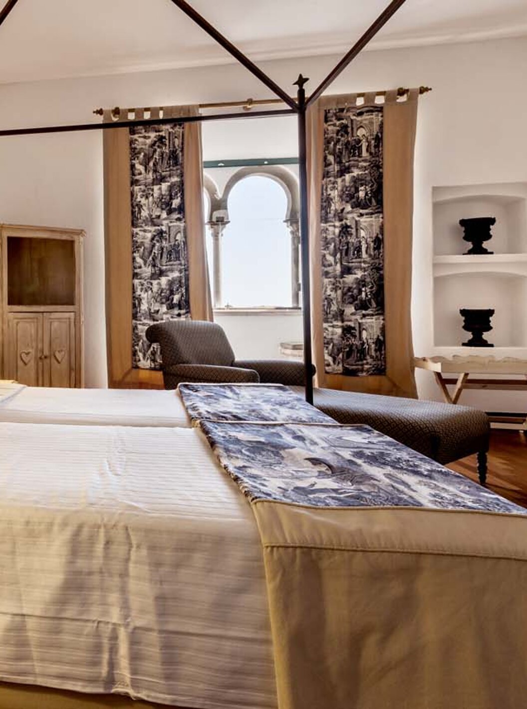 De Standaard Suite van Pousada Castelo Alvito heeft twee aparte bedden, nachtkastjes, een fauteuil en een raam.