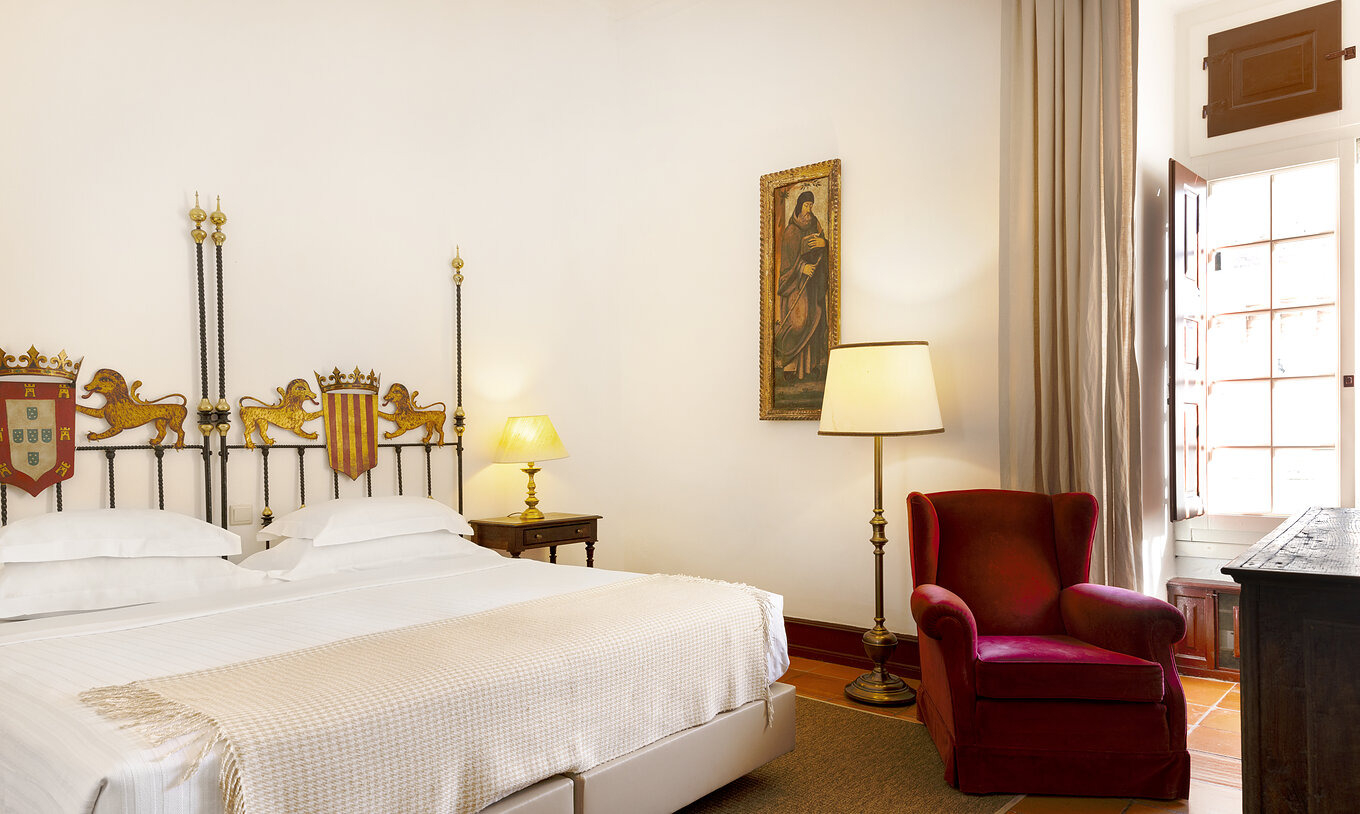 De Superior Kamer heeft een tweepersoonsbed, nachtkastje en fauteuil in Pousada Castelo Estremoz