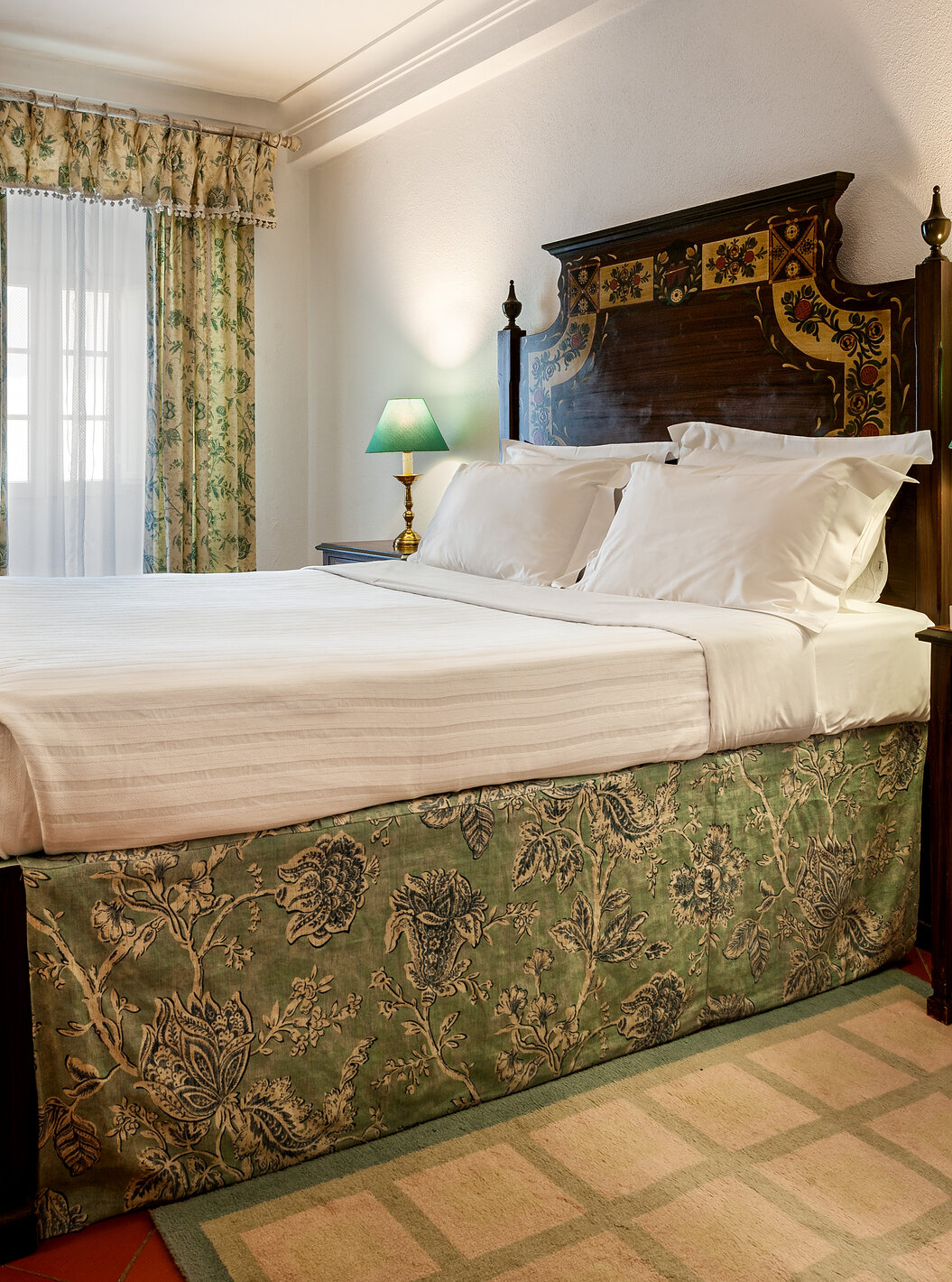 Het Classic Kamer van Pousada Marvão heeft een bed met bloemenpatroon en een donkere houten hoofdbord