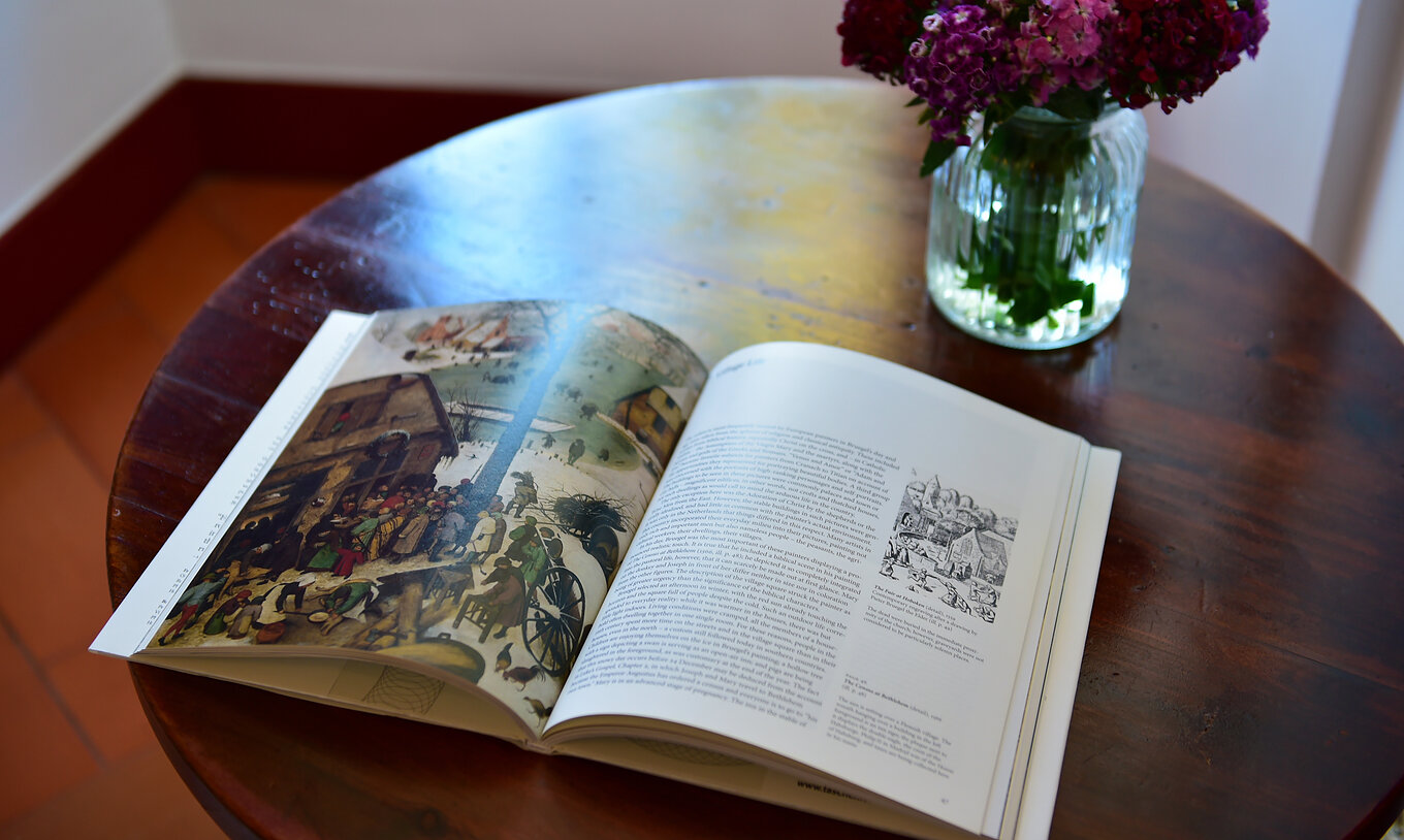 Het Studio Terras van Pousada Marvão heeft een boek en een vaas met roze en rode bloemen