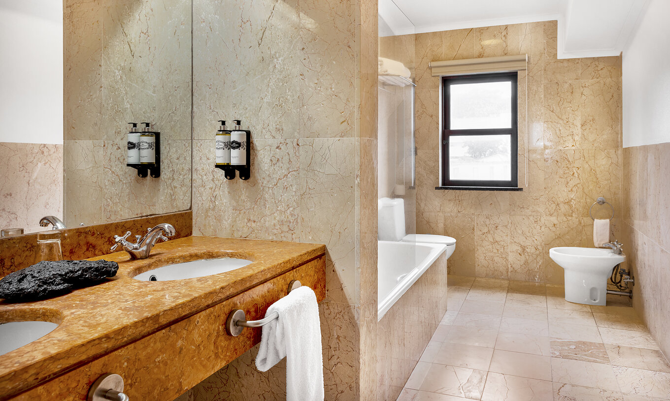 Het Master Suite van Pousada Forte Horta heeft een badkamer met wastafel, spiegel en bad  