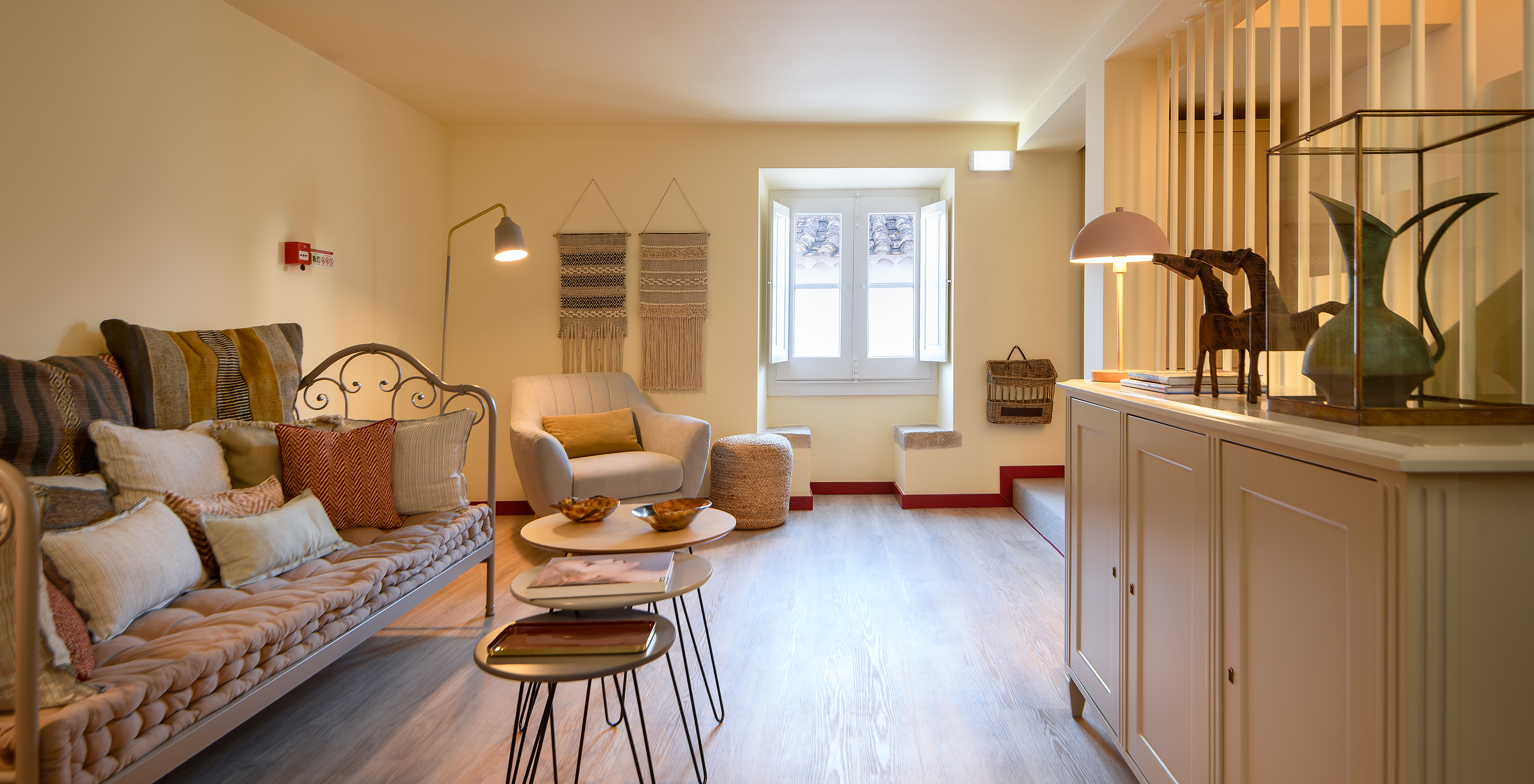 Woonkamer met bank, een fauteuil en een vierkant raam in Casa Lidador - Óbidos, Hotel in het Middeleeuwse Dorp Óbidos