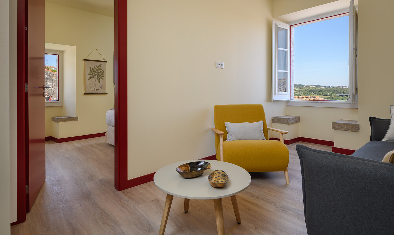De Suite van Casa Lidador - Óbidos heeft een kleine woonkamer met bank, stoel, tafel en een vensterbank van steen
