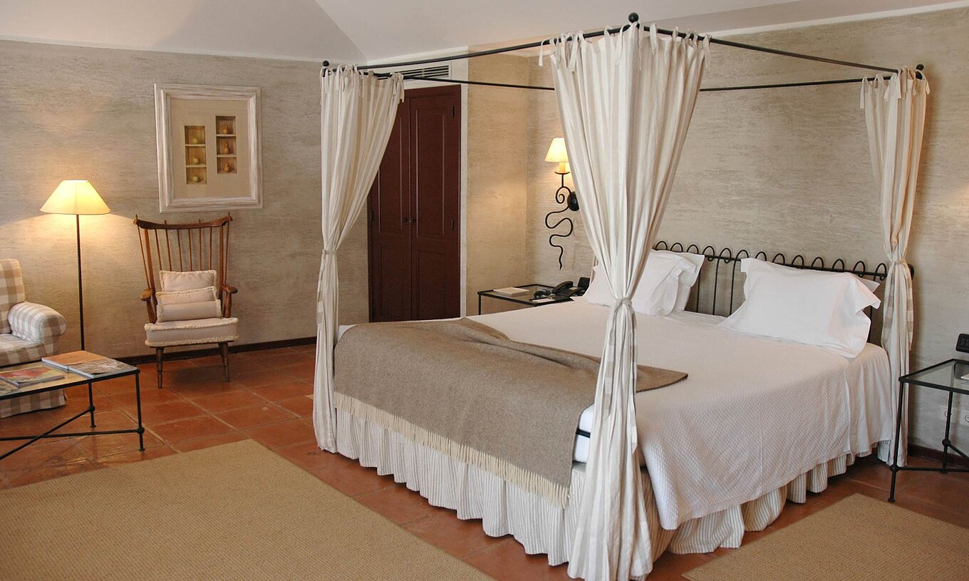 Het Deluxe Kamer van Pousada Convento de Belmonte heeft een tweepersoonsbed met een bruine deken en twee kussens