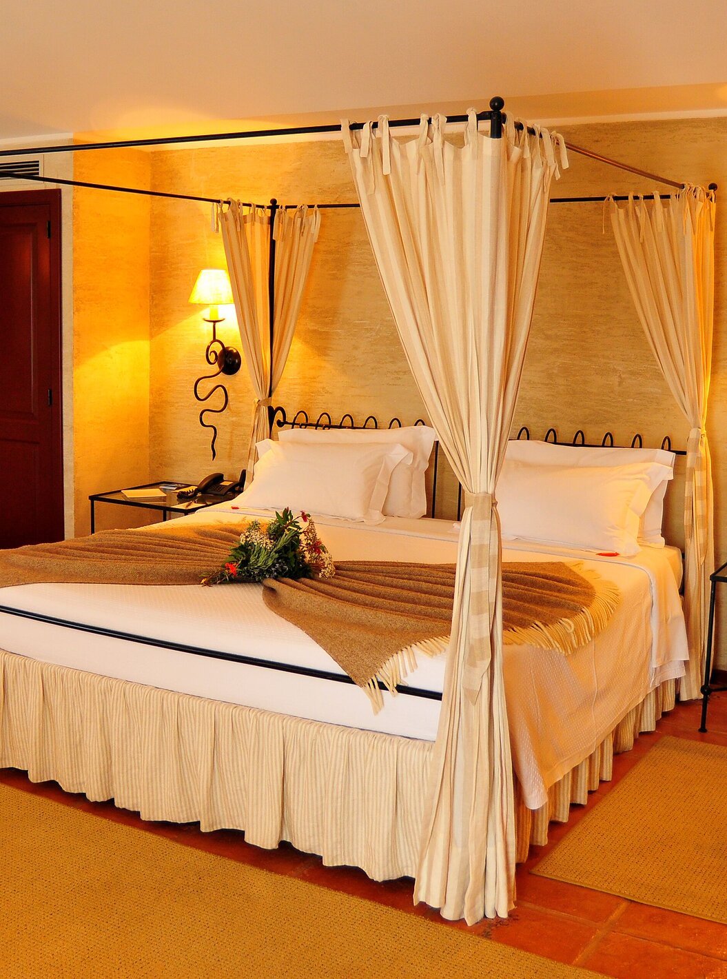 Het Superior Kamer van Pousada Convento de Belmonte heeft een tweepersoonsbed met een deken en bloemen op het bed