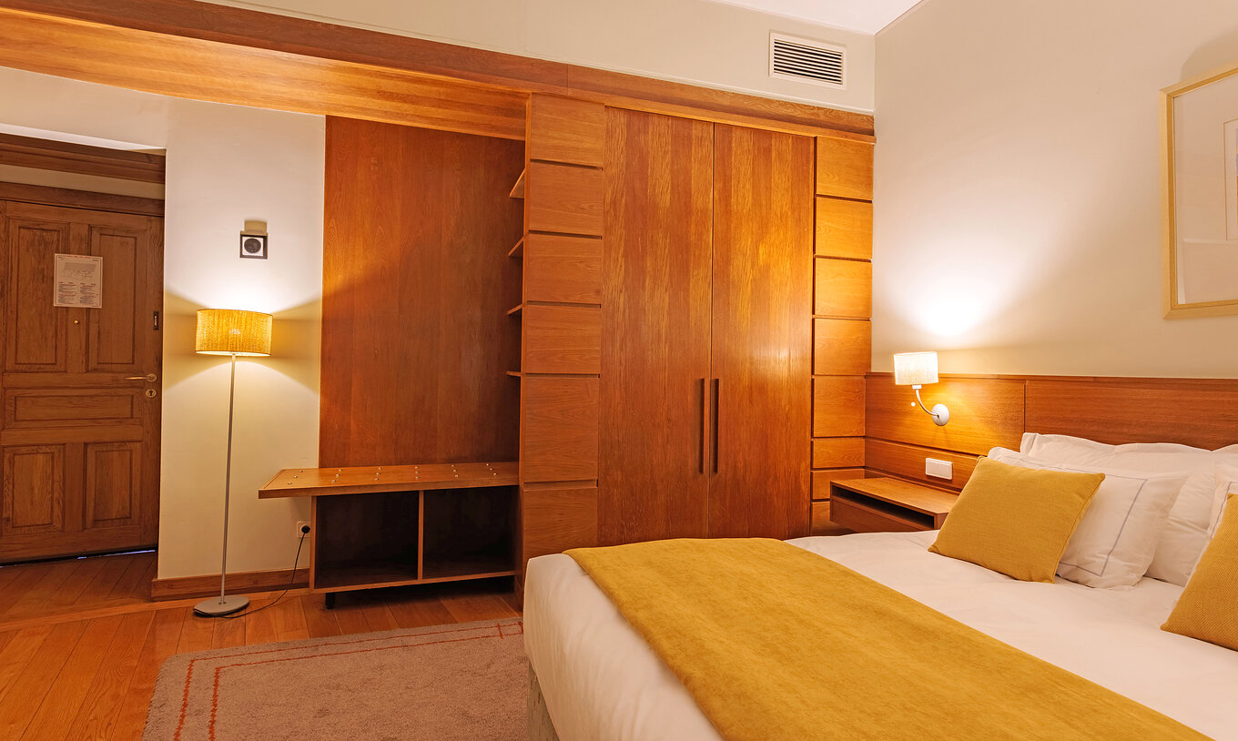 Het Classic Room van Pousada Ourém heeft een tweepersoonsbed met een gele dekbed en een kast naast