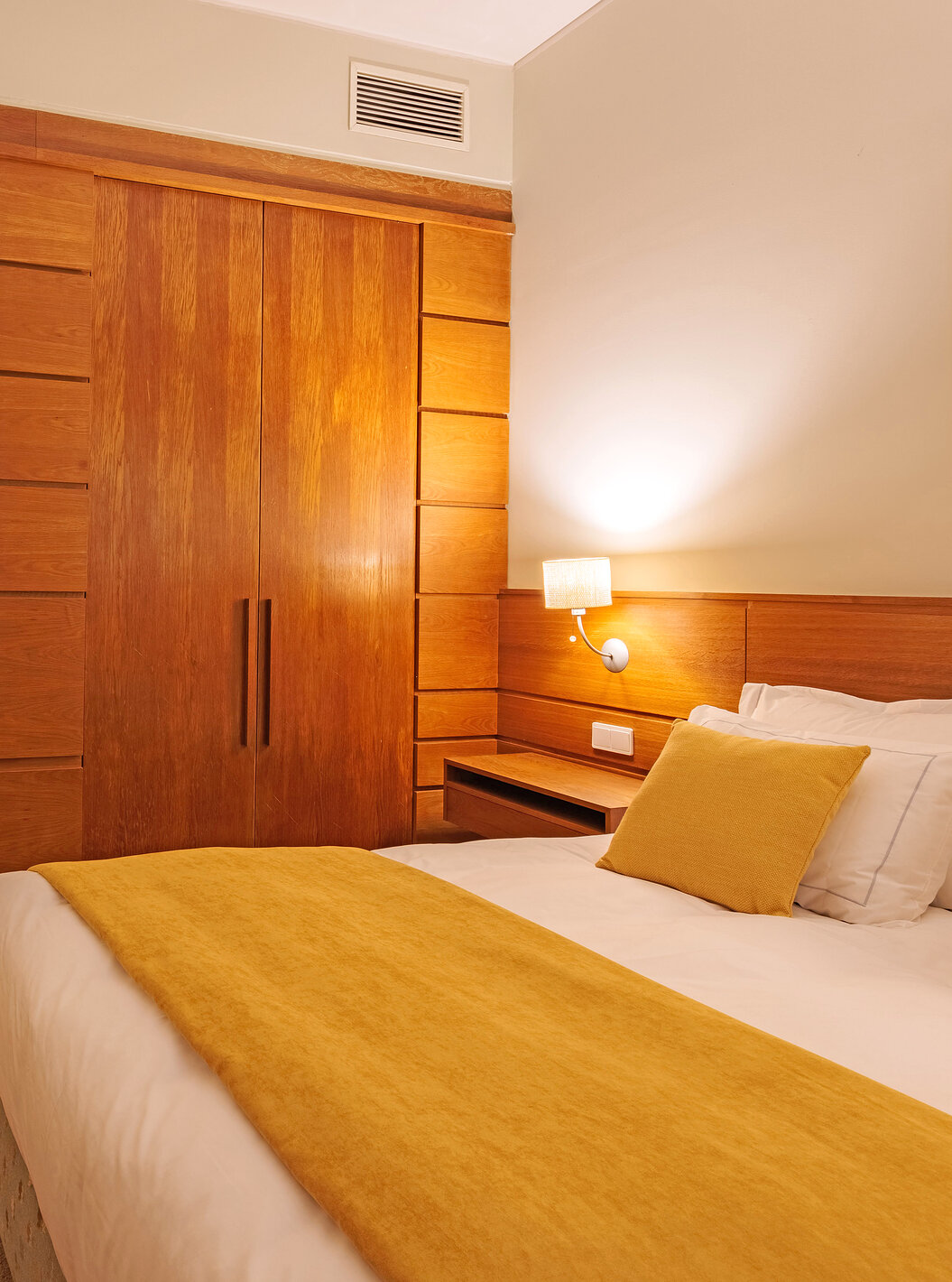 Het Classic Room van Pousada Ourém heeft een tweepersoonsbed met een gele dekbed en een kast naast