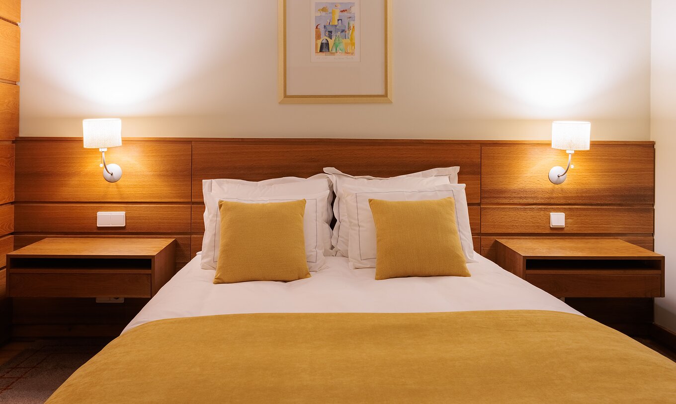 Het Single Room van Pousada Ourém heeft een tweepersoonsbed met twee nachtkastjes en een gele dekbed