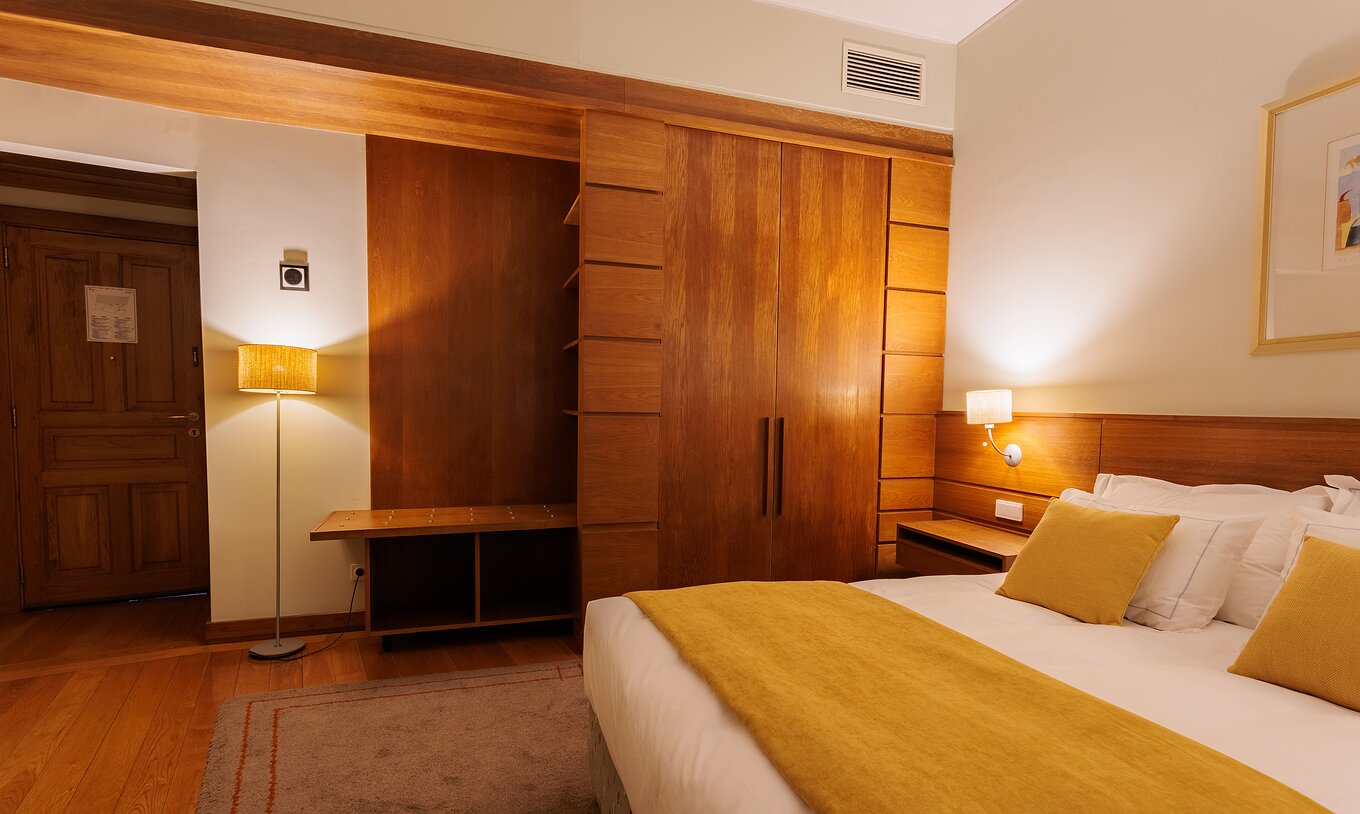 Het Single Room van Pousada Ourém heeft een tweepersoonsbed met een gele dekbed en een kast naast