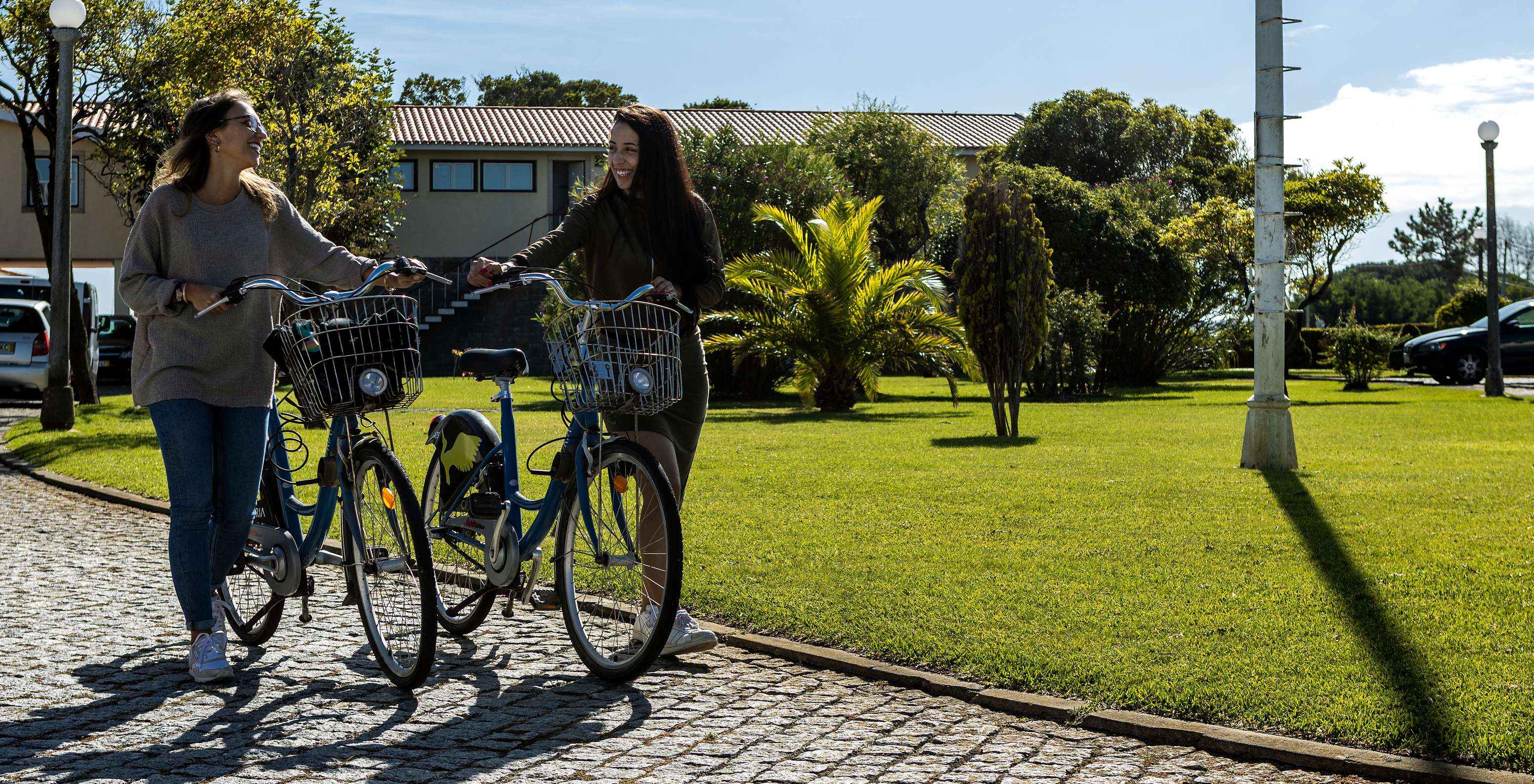 Twee meisjes met fietsen verlaten Pousada Ria - Aveiro met de pousada op de achtergrond