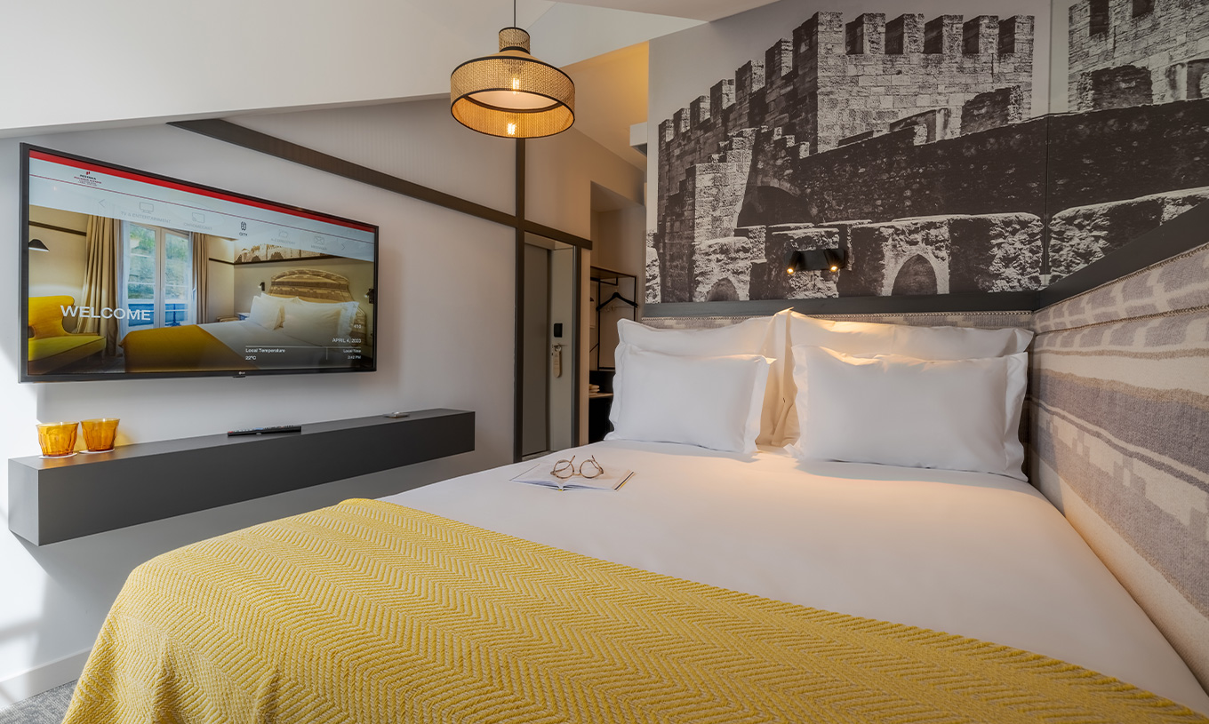 De Mansarda Room van Pousada Alfama heeft een tweepersoonsbed en een tv naast de bed, waar je televisie kunt kijken