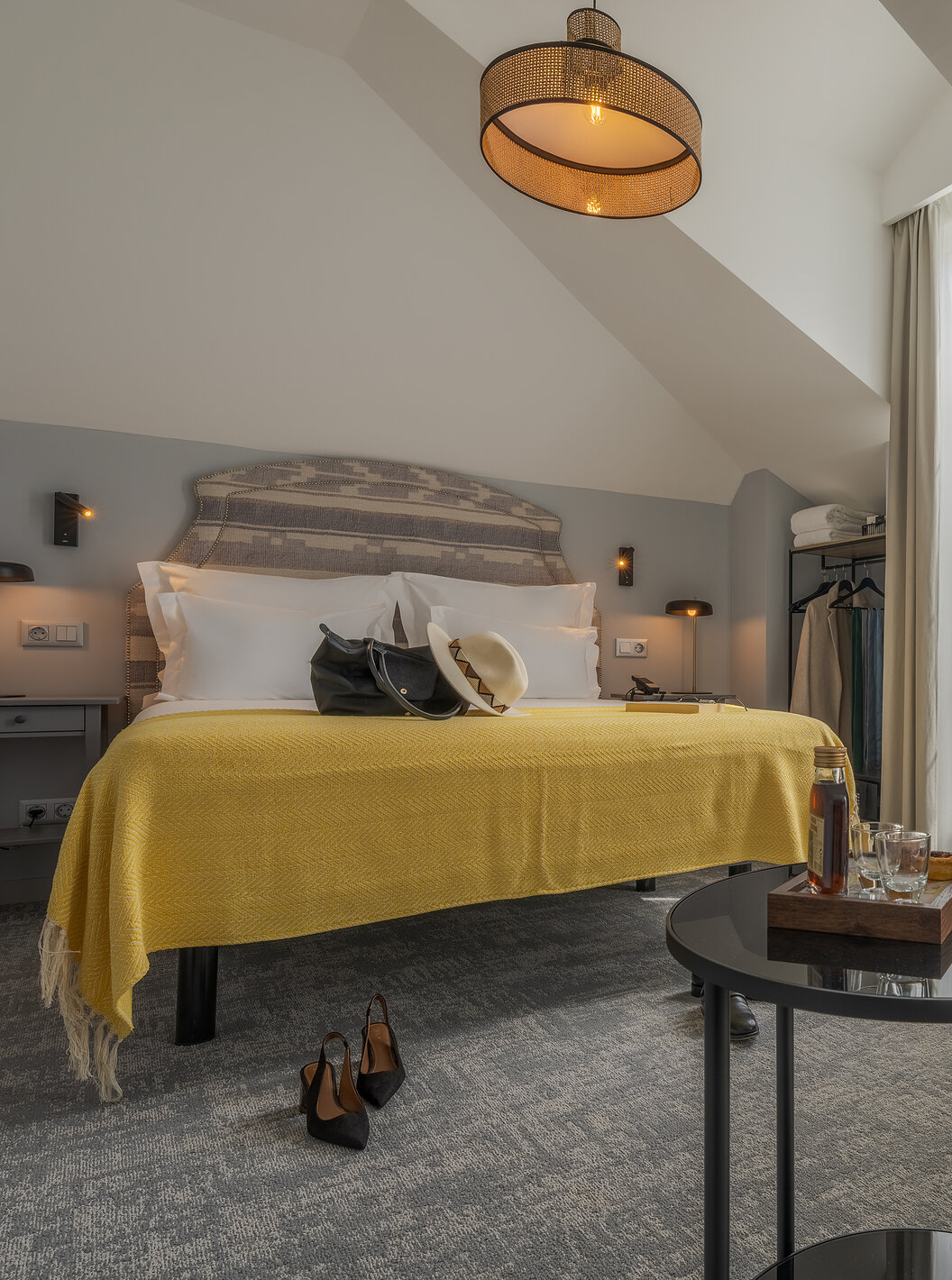 De Junior Suite van de Pousada Alfama heeft een tweepersoonsbed met een gele plaid, een kleine tafel en een gele fauteuil