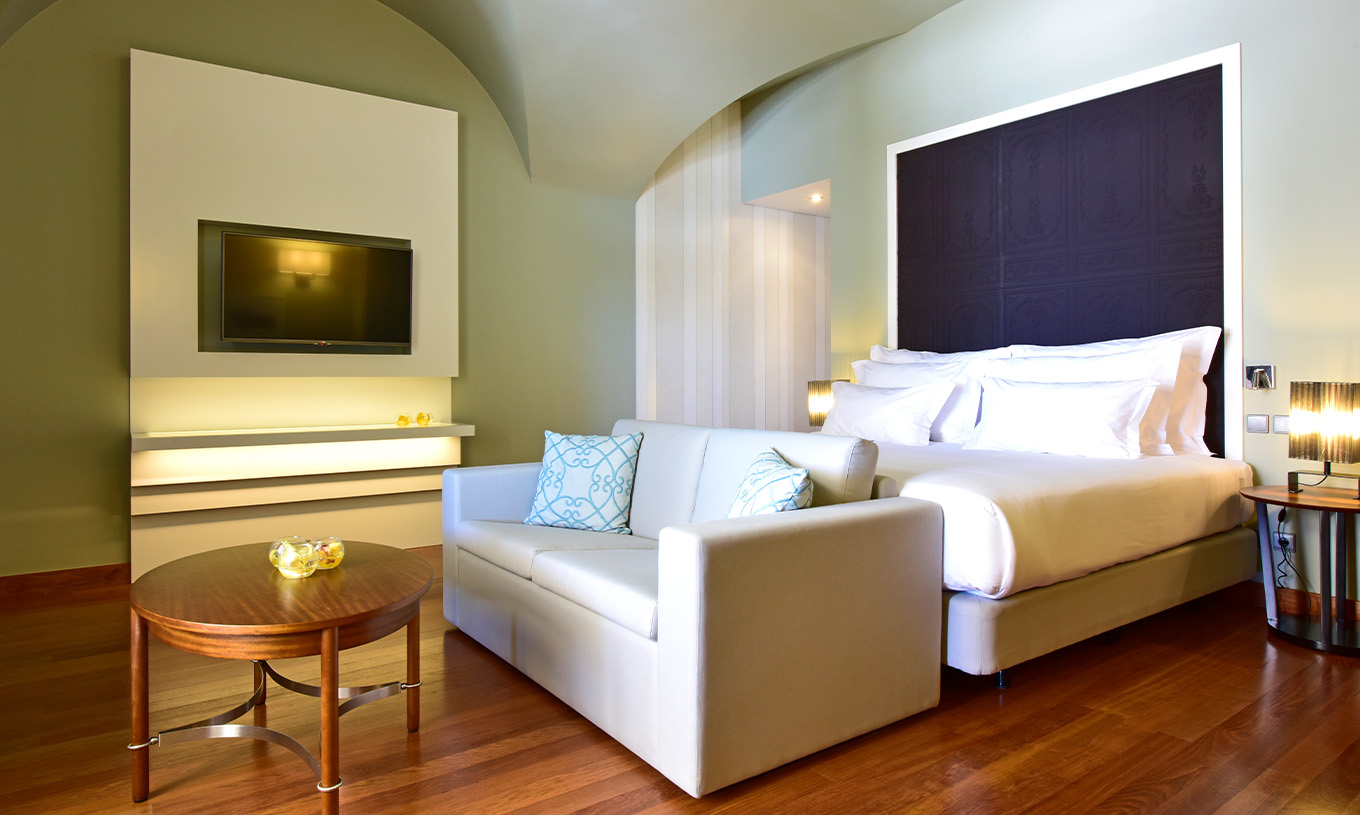 Het Suite King Size Bed van Pousada Lisboa Praça do Comércio heeft een tweepersoonsbed met een bank en een televisie  