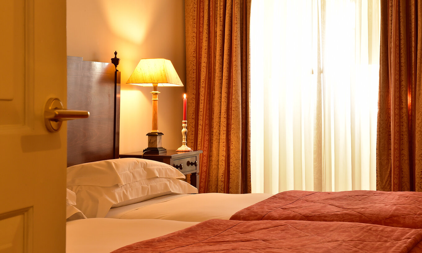Het Classic Room van Pousada Palácio Queluz heeft twee aparte bedden, een lamp en een kaars bij het raam