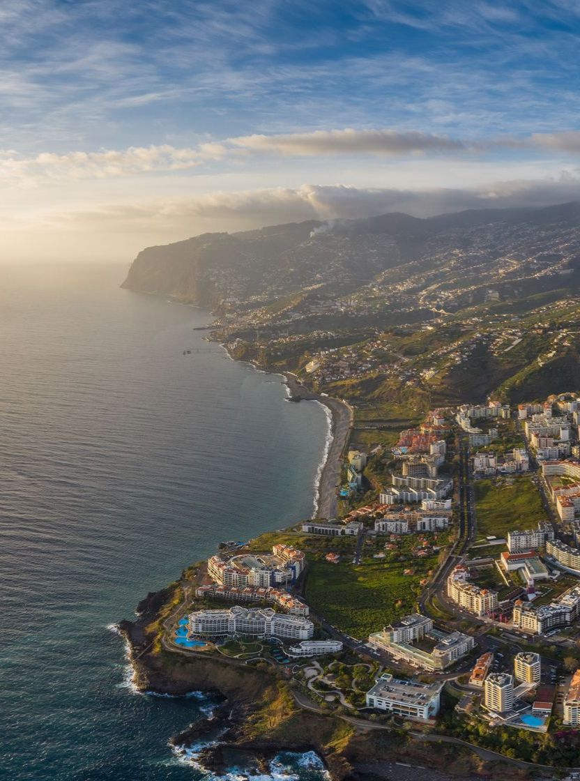 Luchtzicht op de stad Funchal op Madeira, met een haven met boten, dichtbebouwde stedelijke gebieden en bergen op de achtergrond
