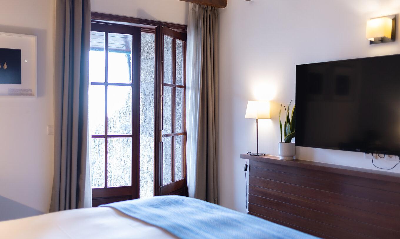 Superior Kamer met Balkon van Pousada Caniçada - Gerês met bed, televisie en raam met uitzicht op de Serra do Gerês