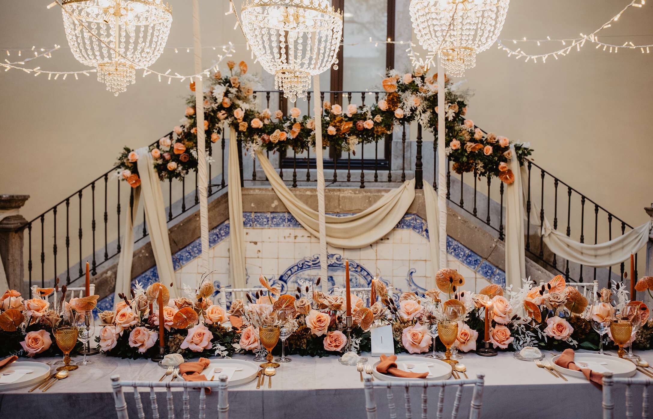 Bruiloft op een historische locatie met romantische decoratie, lange tafel met rozen en kristallen kroonluchters