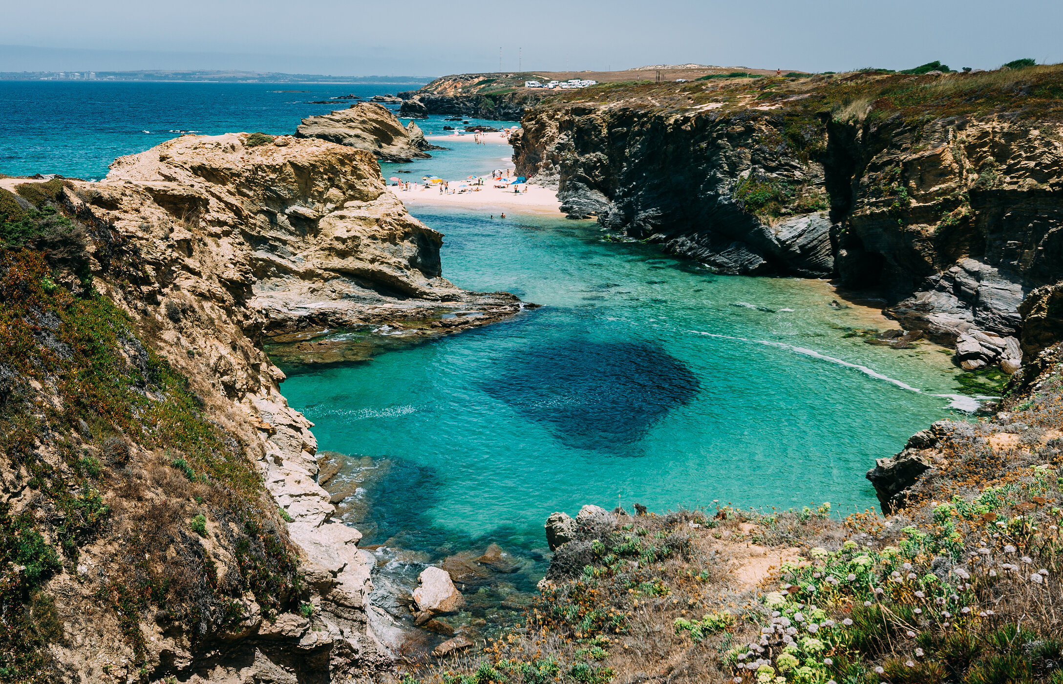 Paisagem paradisíaca da Praia da Samoqueira no Alentejo, escondida entre falésias e com águas cristalinas