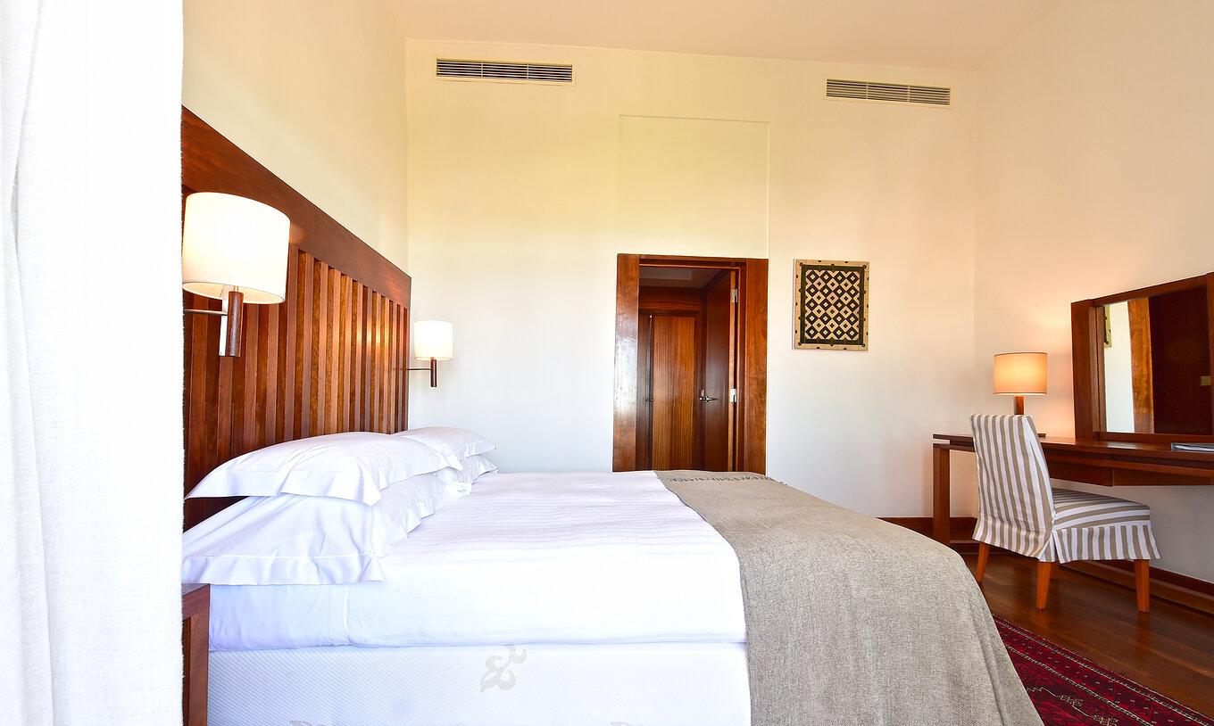 A Suite Standard da Pousada Castelo Alcácer do Sal tem uma cama de casal com uma colcha beje, e uma secretária