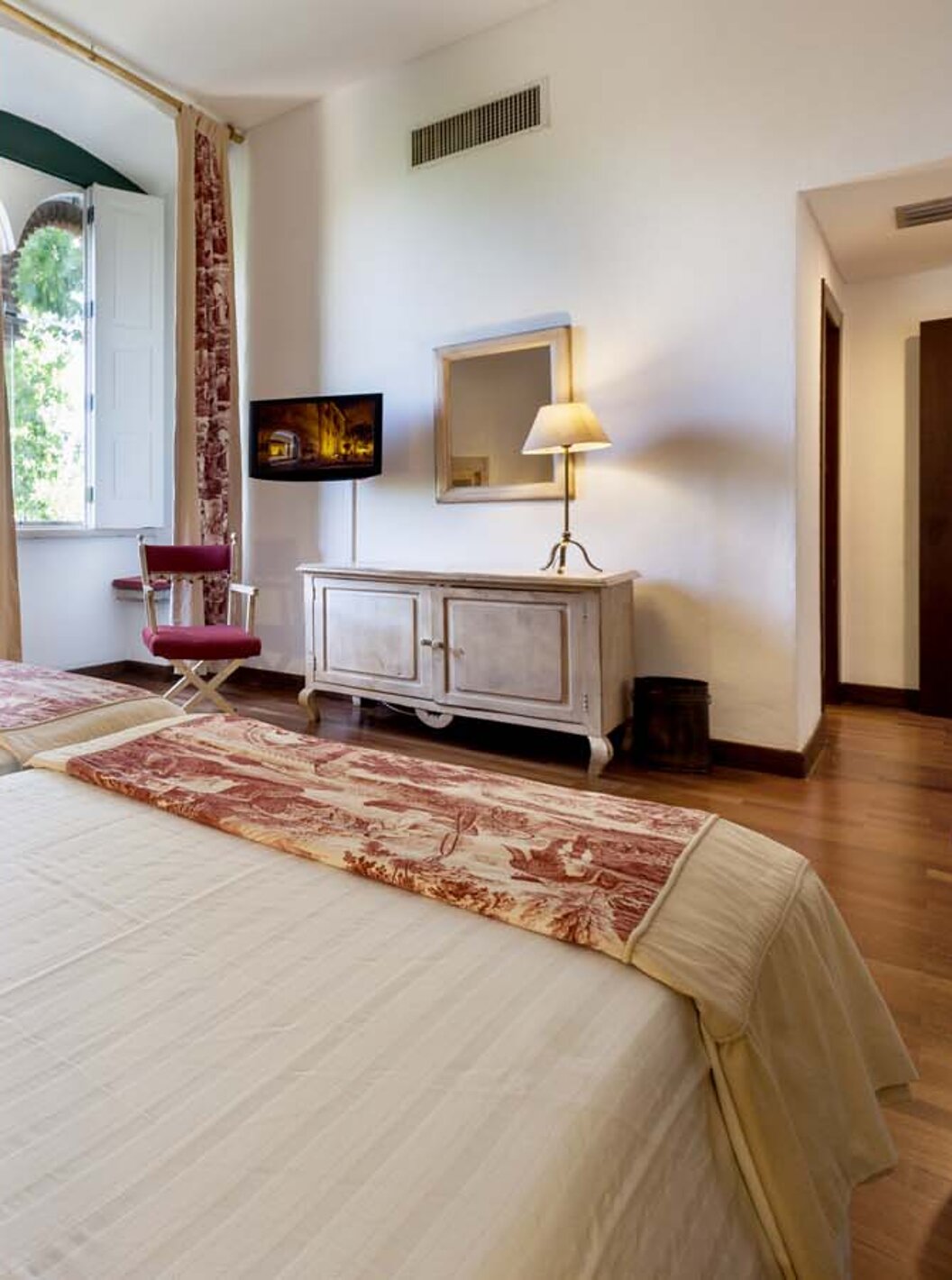 O Quarto Clássico da Pousada Castelo Alvito tem duas camas, uma janela grande, um móvel e uma televisão