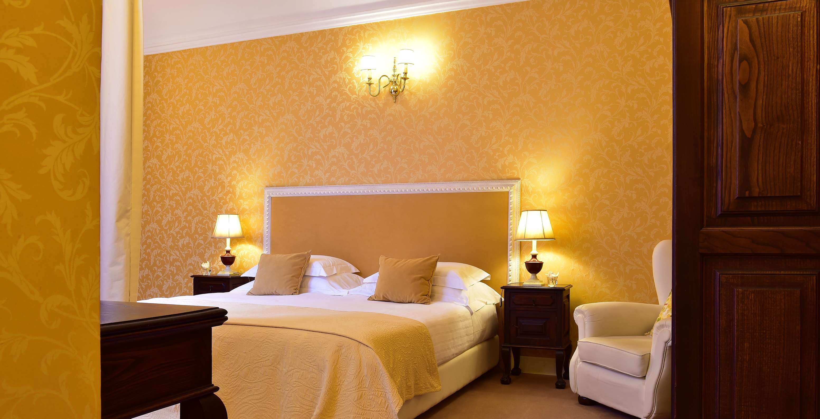 A Suite da Pousada Convento Évora conta com uma cama de casal, com duas mesas de cabeceira e um cadeirão