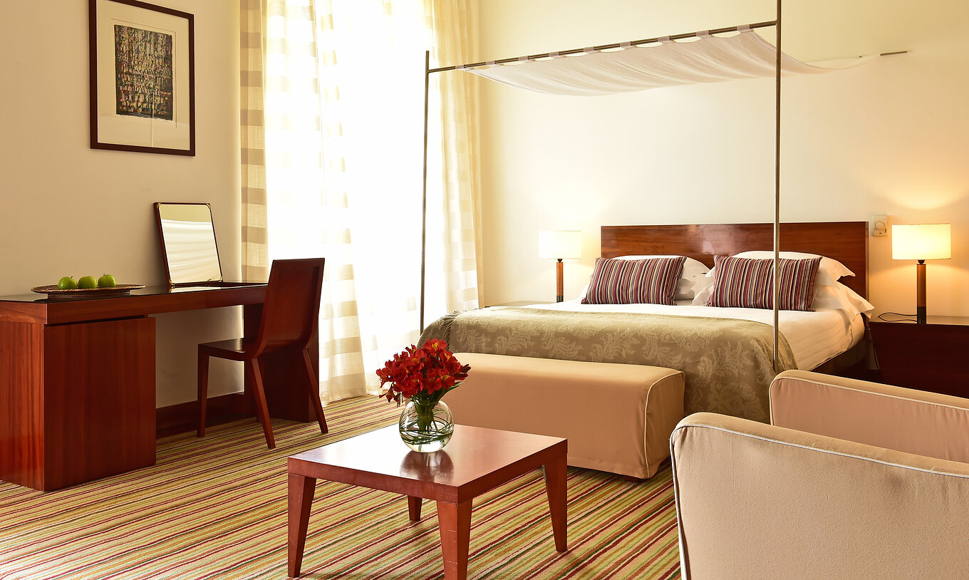 O Quarto Superior Histórico da Pousada Mosteiro Crato tem uma cama de casal com uma banqueta e uma secretária com uma cadeira